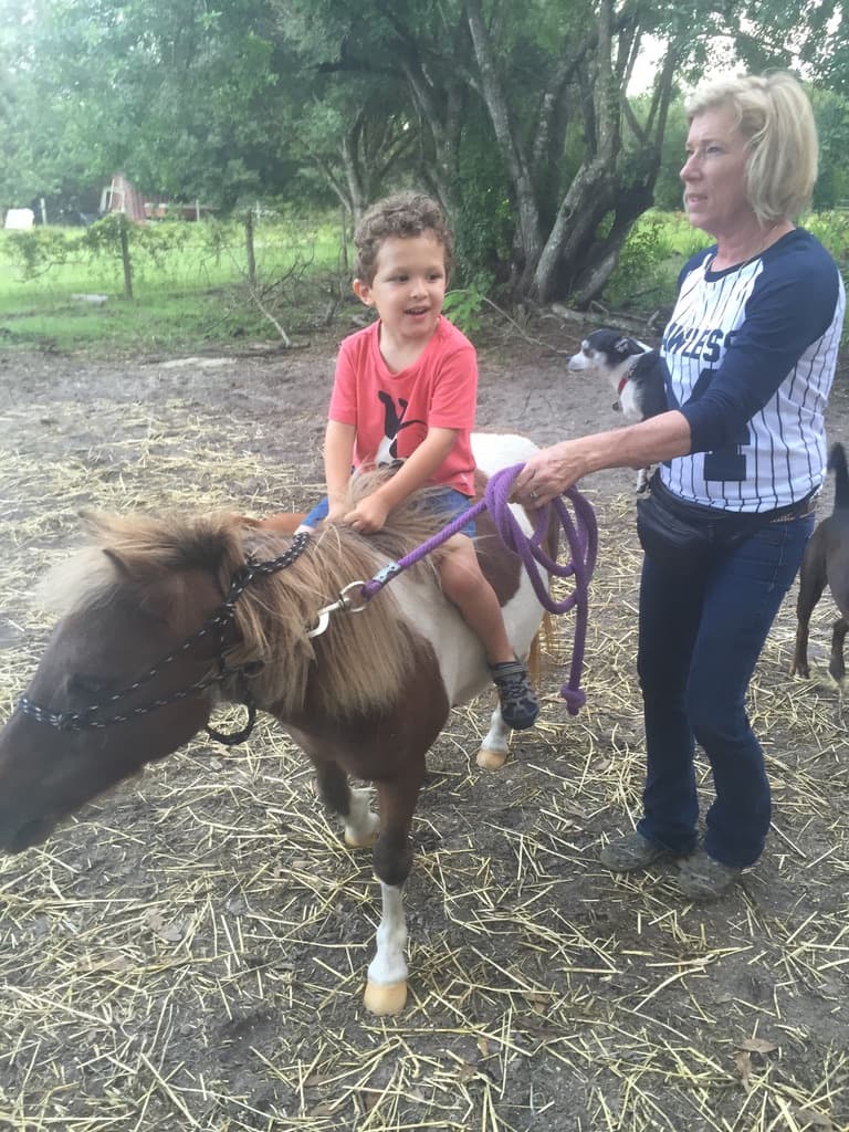Isaac on a pony with Sheryl at the barn